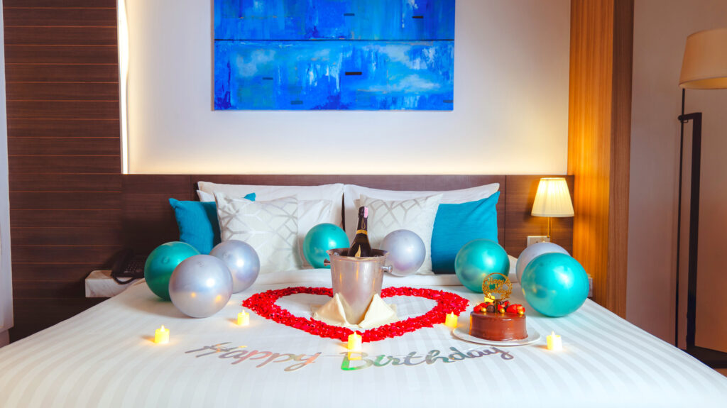 Birthday room decoration with festive balloons, cake decor, and celebratory touches on the bed